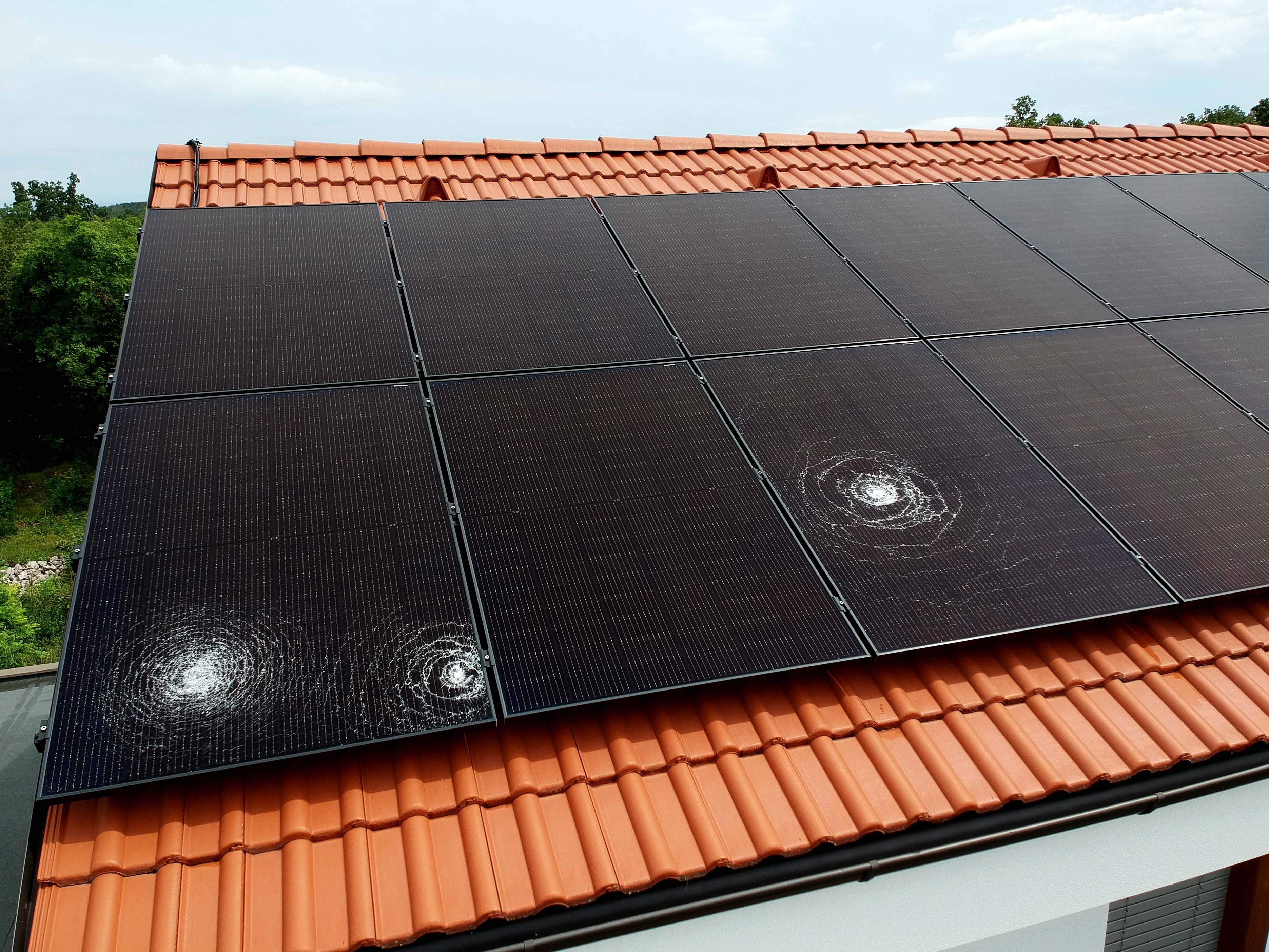Solar panels with visible hail damage on terracotta roof