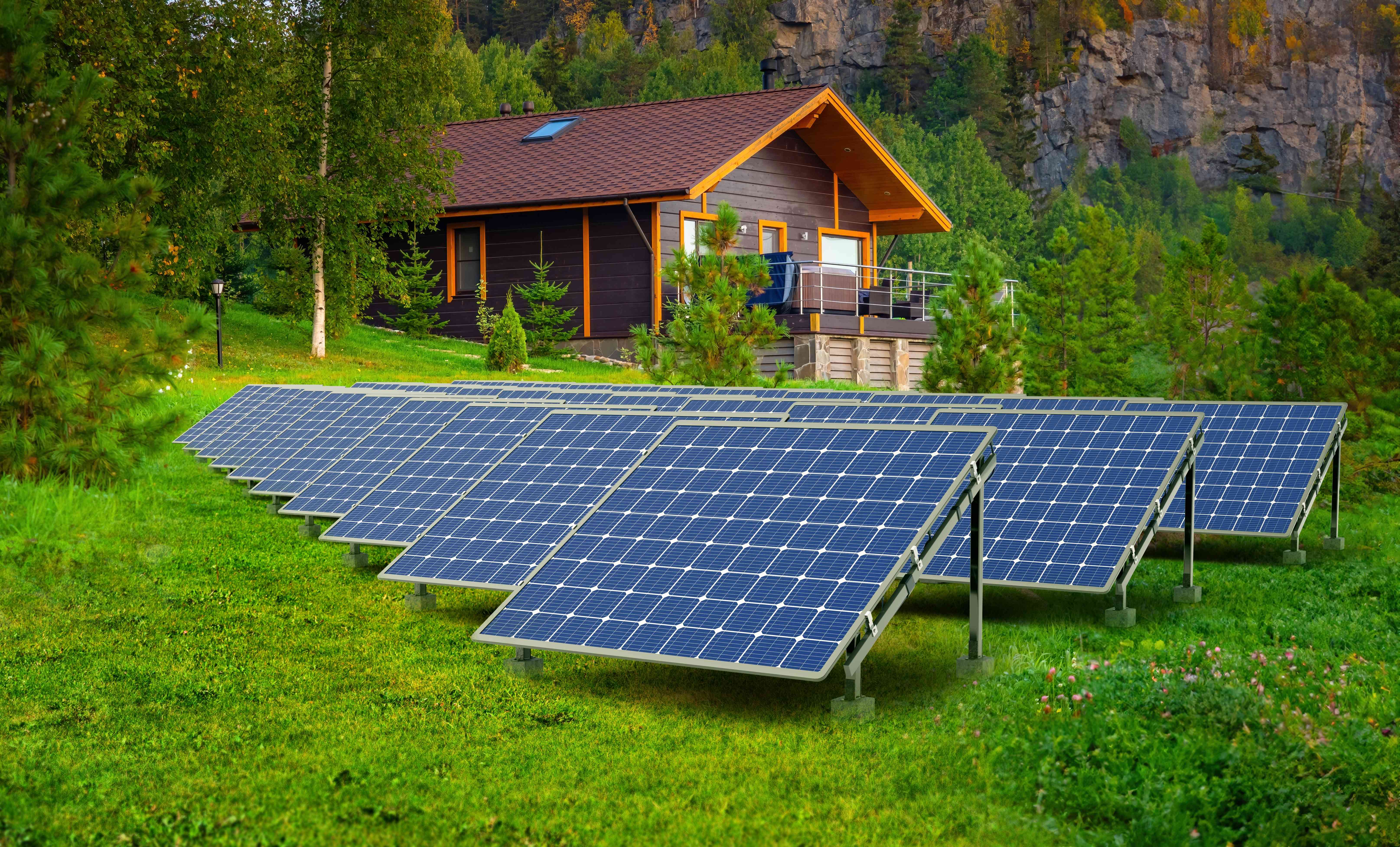 Ground-mounted solar panel array in front of a mountain cabin