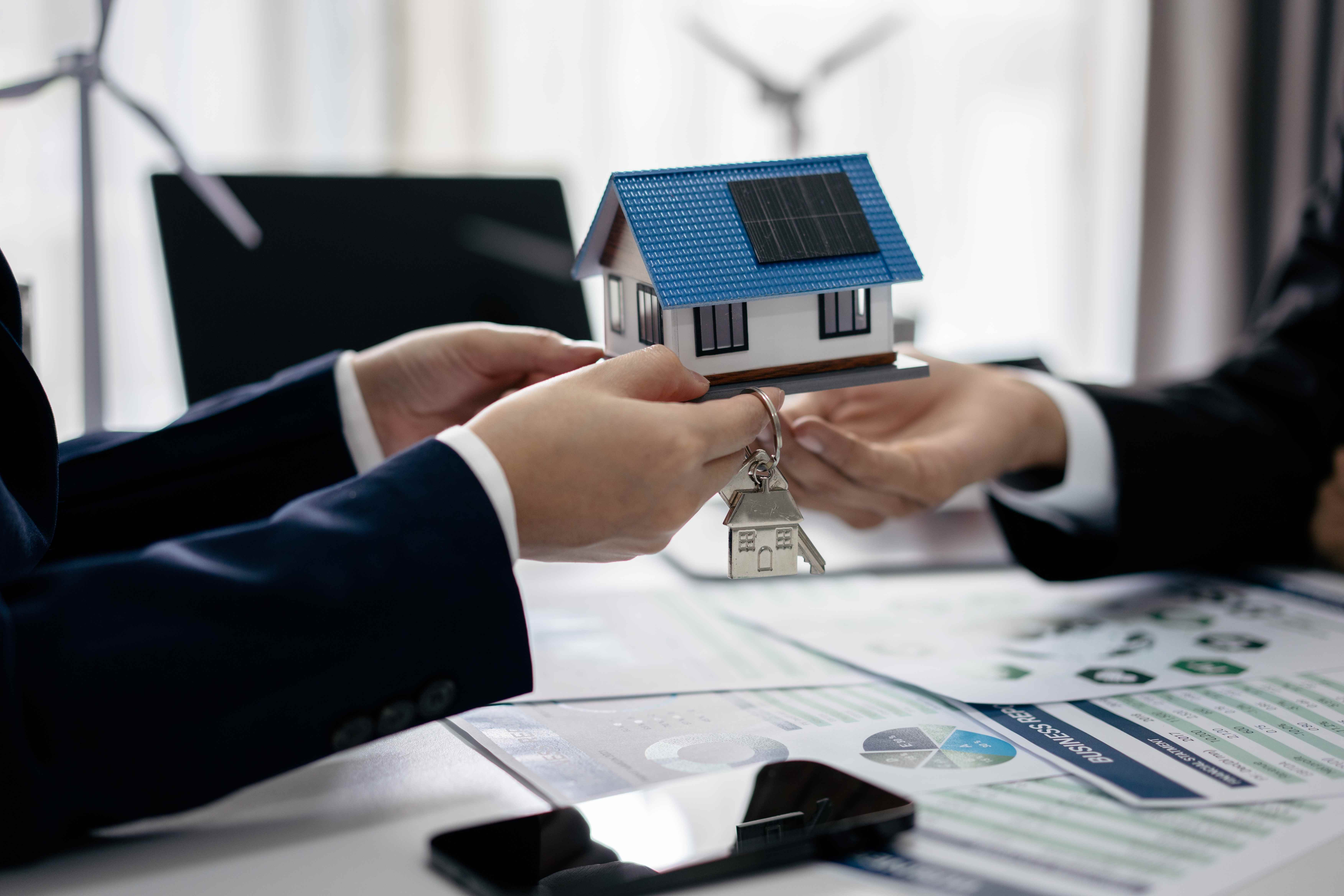 Business professionals discussing a solar home model with documents
